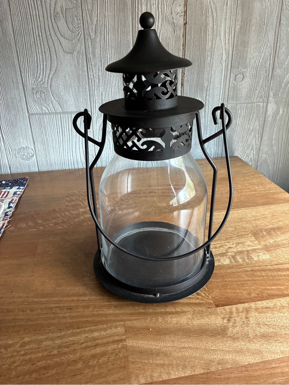 Decorative black metal hurricane lantern/candle lantern. It has a clear glass
